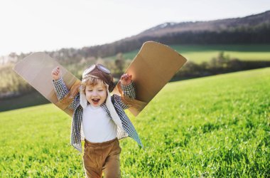 Kanatlı dışında bahar doğa oynarken mutlu yürümeye başlayan çocuk.