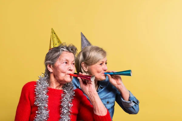 Portret van een senior vrouwen in studio op een gele achtergrond. Party concept. — Stockfoto