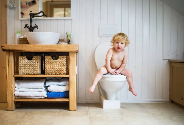 Милий маленький хлопчик сидить на туалеті у ванній . — стокове фото