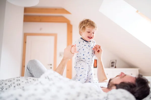 Vater mit einem kleinen Jungen, der zu Hause im Schlafzimmer vor dem Schlafengehen Spaß hat. — Stockfoto