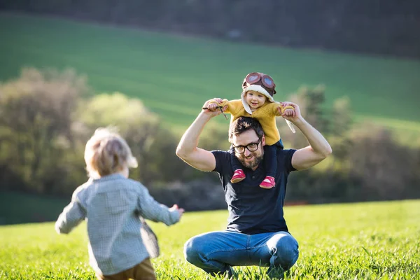 Ein Vater mit seinen Kleinkindern, die draußen Spaß haben, Natur im Frühling. — Stockfoto