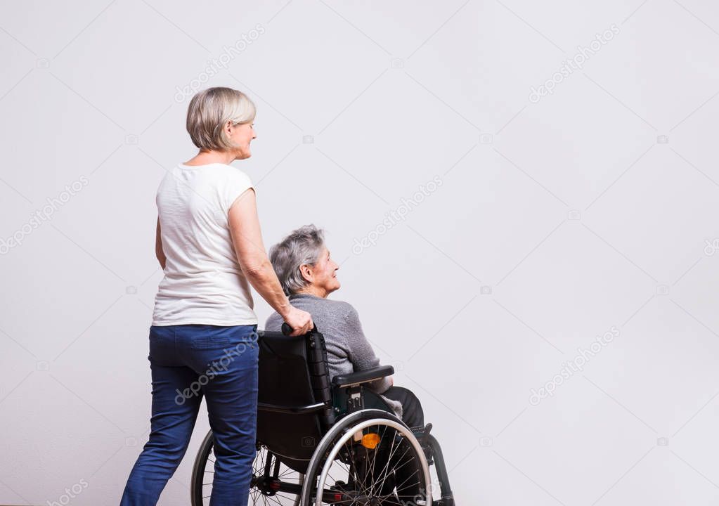 Studio portrait of a senior woman in wheelchair with a carer.
