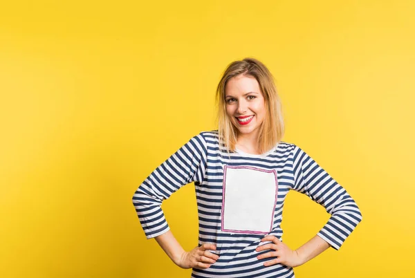 Portret młodej kobiety piękne w studio, miejsce na jej t-shircie. Żółte tło. — Zdjęcie stockowe