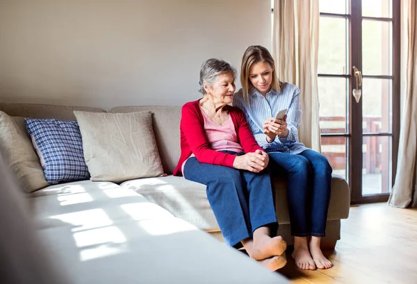Anziani nonna e nipote adulta con smartphone a casa . — Foto Stock