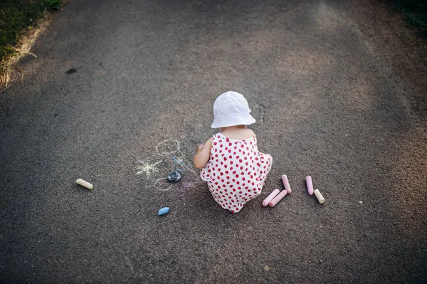 在乡间，一个可爱的蹒跚学步的小女孩的后视镜，粉笔画在路上. — 图库照片