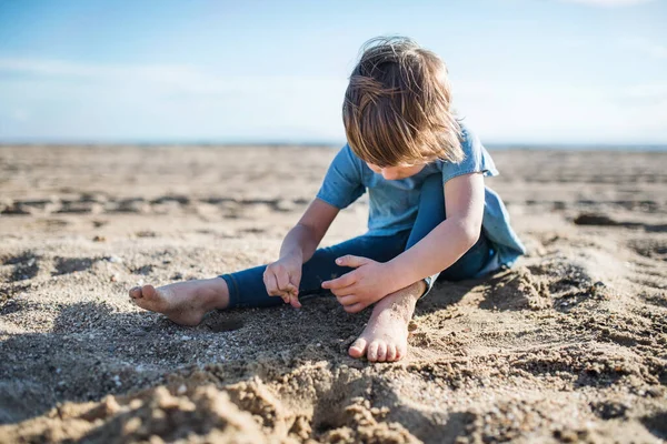 Ein kleines Mädchen spielt draußen im Sand am Strand. — Stockfoto