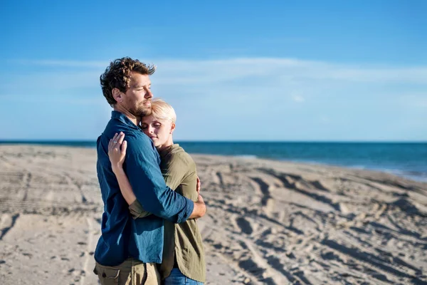 Pareja joven parada al aire libre en la playa, abrazándose. Copiar espacio . — Foto de Stock