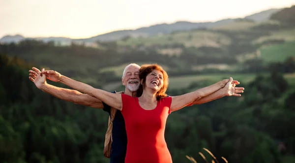 Senior tourist couple travellers with backpacks hiking in nature, resting. — Stock Photo, Image