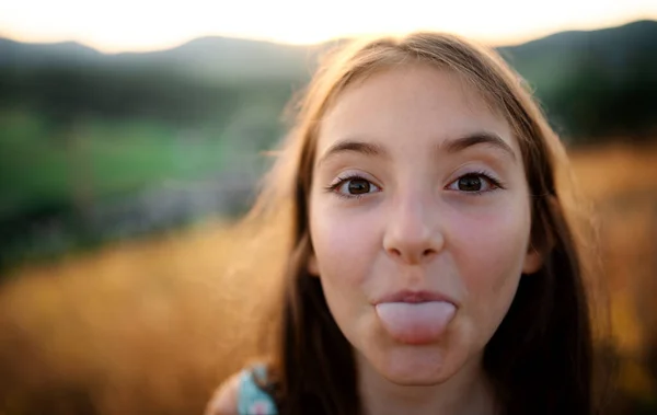 Egy portré egy kislányról a természetben, ahogy kidugja a nyelvét.. — Stock Fotó