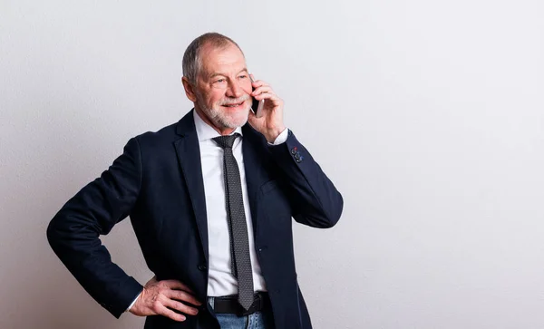 Portrait d'un homme âgé avec smartphone dans un studio, faisant un appel téléphonique . — Photo