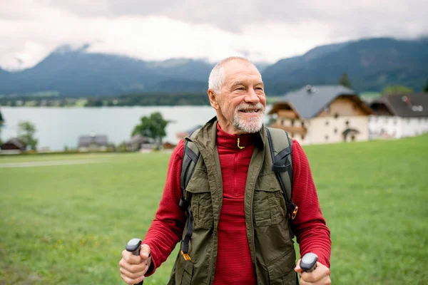 Starszy mężczyzna z kijkami nordic walking wędrujący po przyrodzie, odpoczywający. — Zdjęcie stockowe