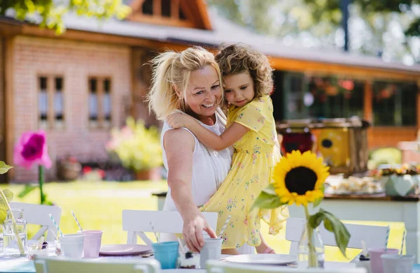 Grand-mère tenant petite fille en plein air sur garden party en été . — Photo