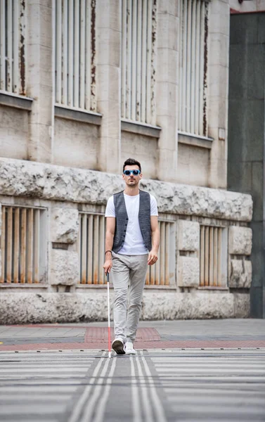 Joven ciego con bastón blanco caminando por la calle en la ciudad . — Foto de Stock