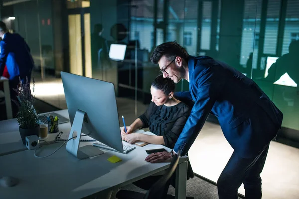 Twee zakenmensen met een computer achter een bureau in een kantoor, werkend. — Stockfoto