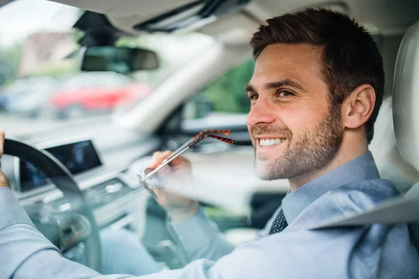 Young businessman with shirt sitting in car. Shot through glass. — Stock Photo, Image