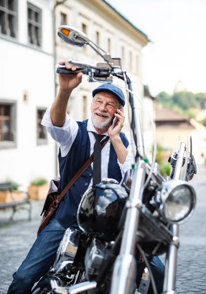 Starszy biznesmen z motocyklem w mieście, korzystający ze smartfona. — Zdjęcie stockowe