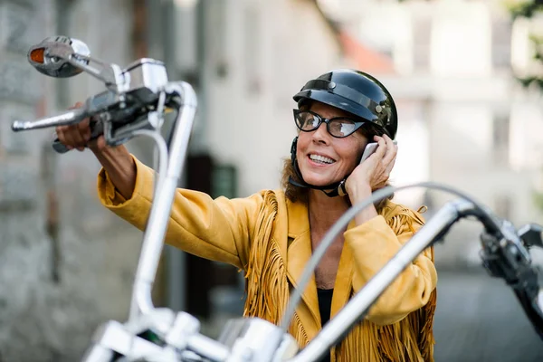 Glada äldre kvinna resenär med motorcykel i stan, ringa telefonsamtal. — Stockfoto