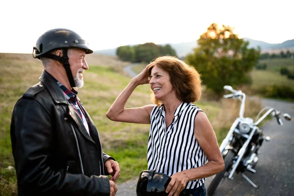 Una coppia di anziani allegri viaggiatori con moto in campagna . — Foto Stock