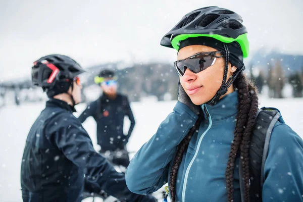 Kobieta rowerzystka górska z przyjaciółmi stojącymi na zewnątrz w zimie. — Zdjęcie stockowe