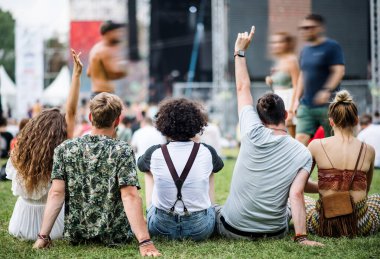 Yaz festivalinde bir grup genç arkadaşın arka planda oturması..