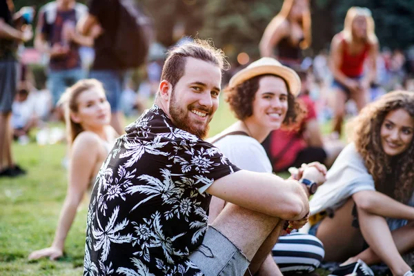 Grupp unga vänner som sitter på marken på sommarfestivalen. — Stockfoto