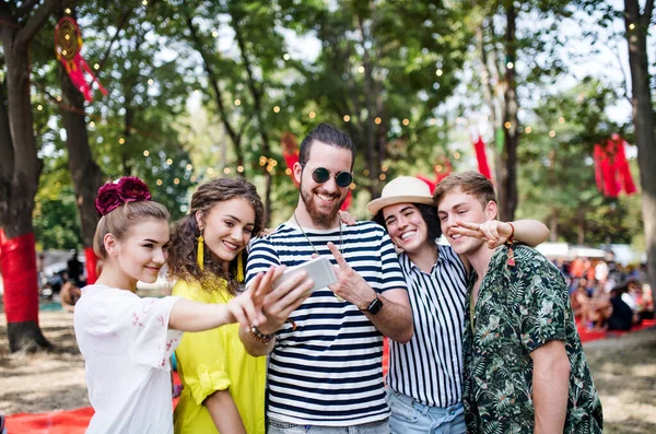 Group of young friends with smartphone at summer festival, taking selfie. — Stock Photo, Image