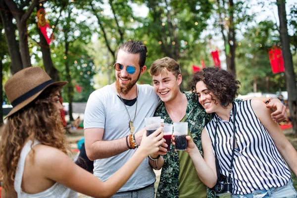 Grupo de jóvenes amigos con bebidas en el festival de verano, de pie . — Foto de Stock