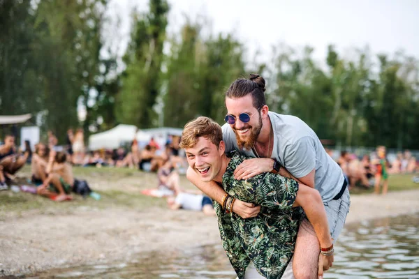 Mladí muži přátelé se baví na letním festivalu, stojí v jezeře. — Stock fotografie