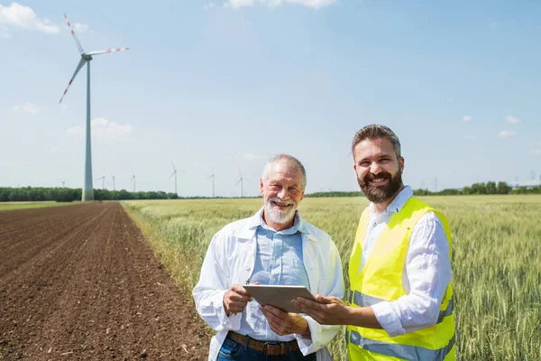 Ingenieure stehen auf Windpark und machen sich Notizen. — Stockfoto