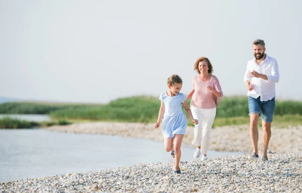 Famille multigénération en vacances à pied au bord du lac, en courant . — Photo