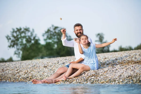Padre e figlia piccola in vacanza seduti vicino al lago . — Foto Stock