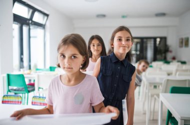 Kantinde plastik tepsiler ile neşeli küçük okul çocuklar grubu, yürüyüş.