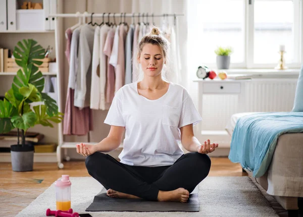 Junge Frau macht zu Hause Yoga-Übungen und meditiert. — Stockfoto