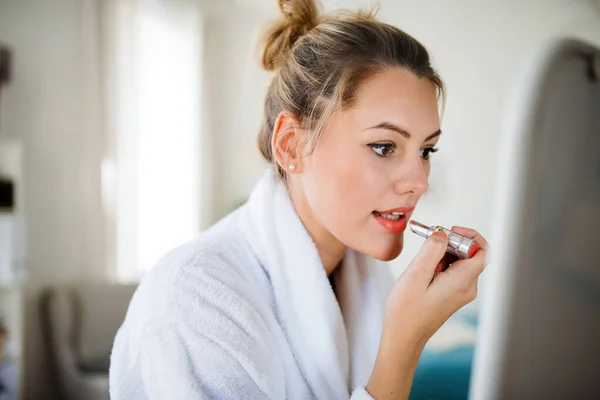 Jeune femme à l'intérieur à la maison le matin, mettre du rouge à lèvres . — Photo