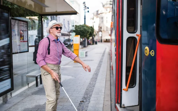Senior blind man with white cane getting on public transport in city. — Stock Photo, Image