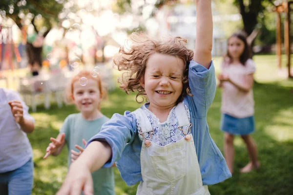 Kleine kinderen die in de zomer buiten in de tuin staan te spelen. — Stockfoto