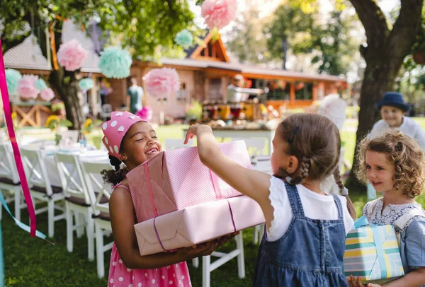 Portrait de petite fille avec des amis et des cadeaux en plein air dans le jardin en été . — Photo