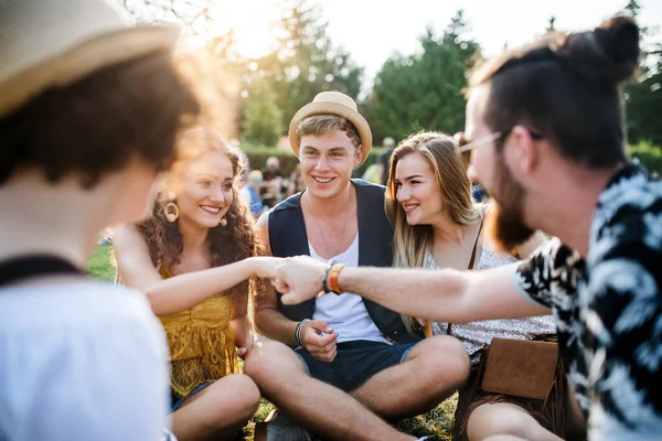 Группа молодых друзей, сидящих на земле на летнем фестивале . — стоковое фото