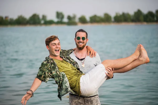 Mladí muži přátelé se baví na letním festivalu, stojí v jezeře. — Stock fotografie