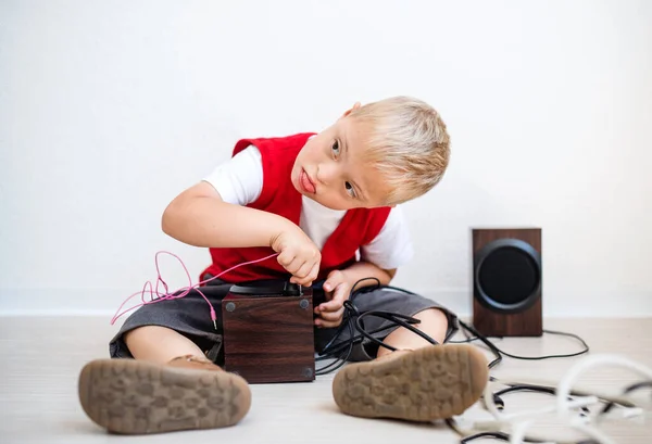 Portrait d'un écolier trisomique assis par terre, utilisant des haut-parleurs . — Photo