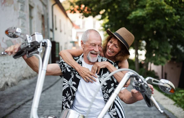 Um alegre casal de idosos viajantes com moto na cidade . — Fotografia de Stock