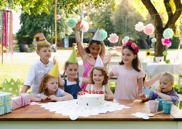 Síndrome de Down niño con amigos en fiesta de cumpleaños al aire libre en el jardín . —  Fotos de Stock
