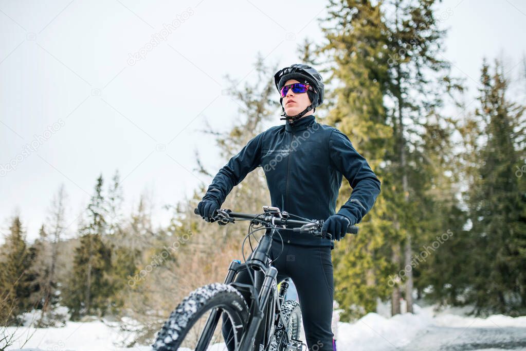 Front view of mountain biker standing outdoors in winter nature.