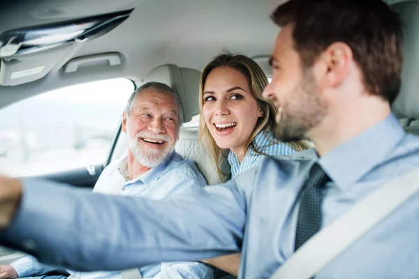 Jeune couple avec père aîné assis en voiture, conduisant et parlant . — Photo