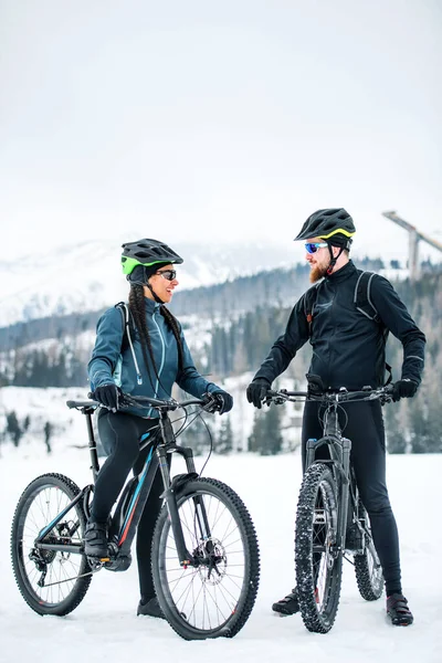 Dva horští cyklisté s jízdními koly odpočívající venku v zimě. — Stock fotografie