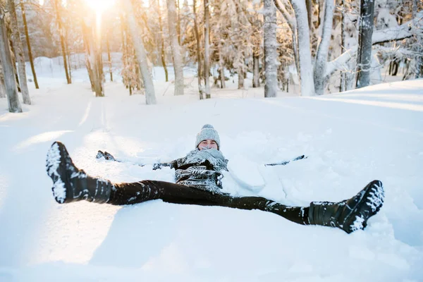 Young man having fun in snow outdoors in winter, lying in snow. — Stock Photo, Image