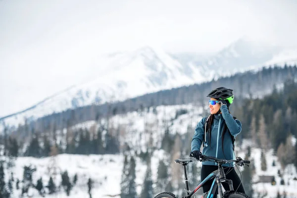 Mountainbikerin steht draußen in der winterlichen Natur. — Stockfoto