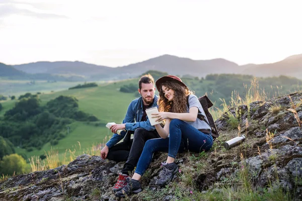 ハイキングの後に休憩し、自然の中で座って若い観光客のカップル旅行者. — ストック写真