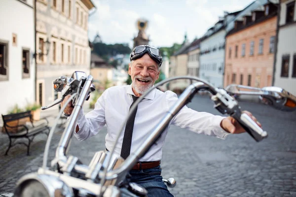 Un homme d'affaires avec une moto en ville, regardant la caméra . — Photo