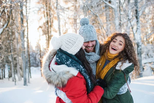 En grupp glada unga vänner som har roligt utomhus i snön i vinterskogen. — Stockfoto